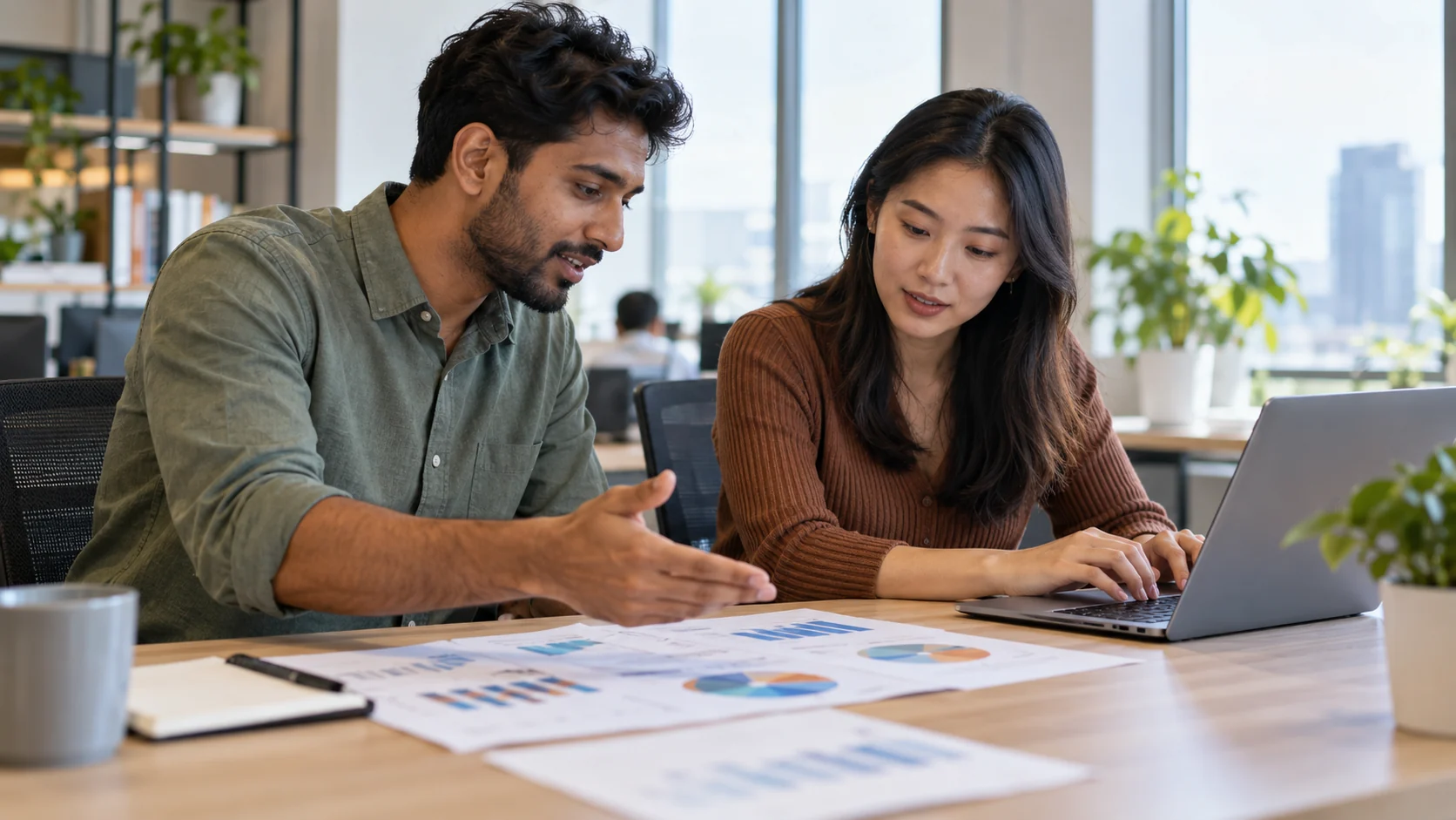 Two marketing analysts discussing a dashboard and printed performance chart.
